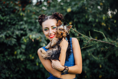 Young beautiful woman with Yorkshire Terrier near green bushの写真素材