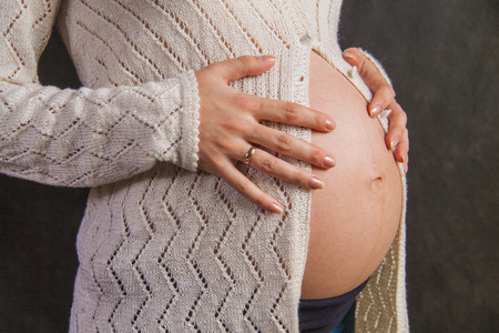 Close up pregnant woman belly isolated on the black background.