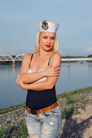 Young girl wearing jeans and sailor cap on the river shoreの写真素材