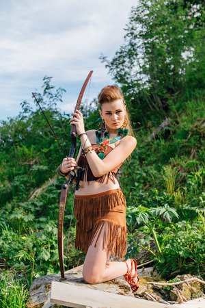 The young beautiful girl amazon aiming a bow while hunting in the forest, mythical character, a fairy tale, the legendの写真素材
