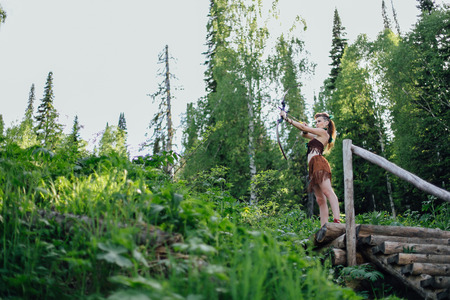 The young beautiful girl amazon aiming a bow while hunting in the forest, mythical character, a fairy tale, the legendの写真素材