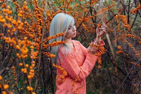 Portrait of a young woman with blue hair in a bush of sea-buckthornの写真素材
