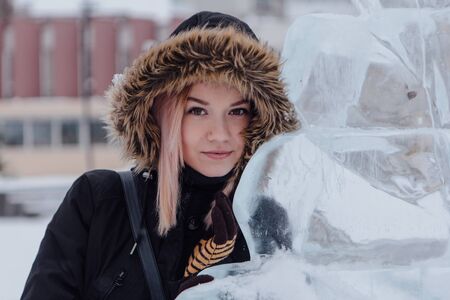 Winter fashion. Portrait of a beautiful young woman in warm clothes outdoor near the ice sculpture.の写真素材