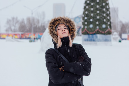 Winter fashion. Portrait of a beautiful young woman in warm clothes outdoor near Christmas tree