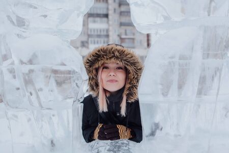 Winter fashion. Portrait of a beautiful young woman in warm clothes outdoor near the ice sculpture.の写真素材