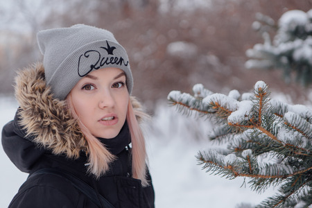 Winter fashion. Portrait of a beautiful young woman in warm clothes outdoor near Christmas treeの写真素材