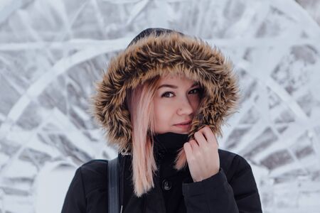Winter fashion. Portrait of a beautiful young woman in warm clothes outdoor near the ice sculpture.