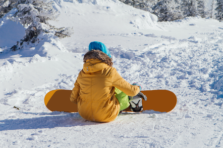 Back view of a snowboarder girl on a snowhillの写真素材