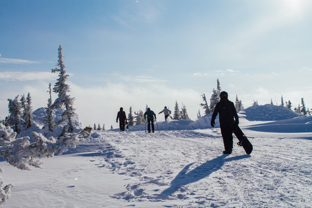 People in ski suit holding snowboards on a snowhillの写真素材
