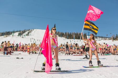 Sheregesh, Kemerovo region, Russia - April 16, 2016: Grelka Fest is a sports and entertainment activity for ski and snowboard riders in bikini in Russia, Sheregesh. Group of young happy pretty women on a snowboard in colorful bikini with flags.のeditorial素材
