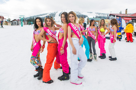 Group of young happy pretty women in snowboard pants and colorful bikini near the mountain.のeditorial素材