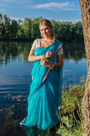 Beautiful european woman in traditional indian sari near the lake
