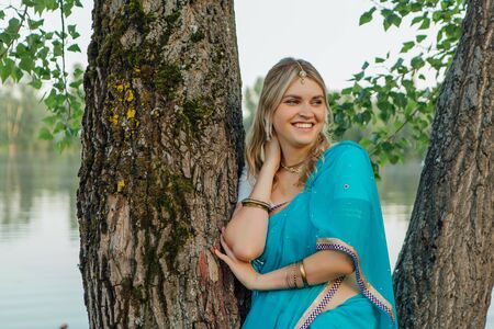 Beautiful european woman in traditional indian sari near the treeの写真素材
