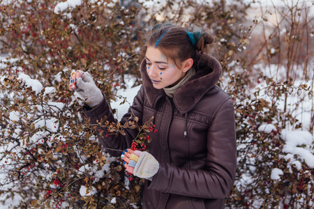 Winter portrait of a girl with bright make up and blue stars on face with barberryの写真素材