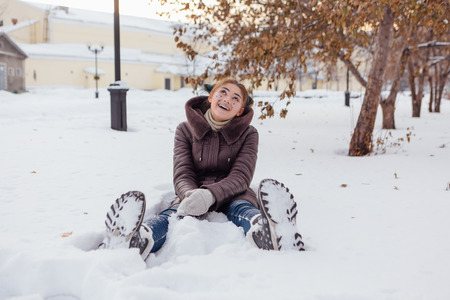 Winter portrait of a girl with bright make up and blue stars on face sitting in snowの写真素材