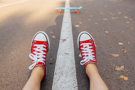 Close up of feet of a girl in red sneakers and blue penny skate board with pink wheels on the background. Urban scene, city life. Sport, fitness lifestyle.の写真素材