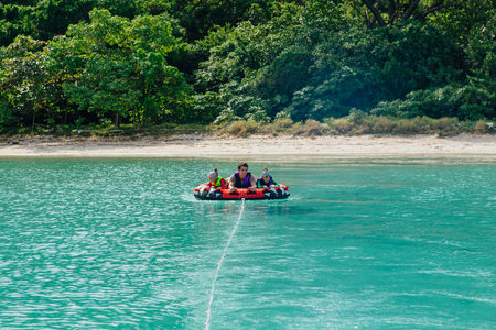 Chonburi, Thailand - November 26, 2013 :: Father with two small daughters twins on water attraction donut boat during summer vacationsのeditorial素材