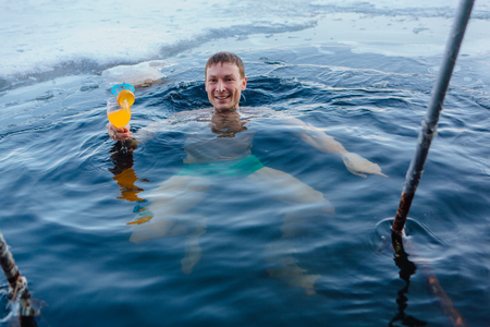 Novokuznetsk, Kemerovo region, Russia - 23 Feb, 2017 : White beaches of Siberia is an enterteiment activity where people playing beach games dressed in bikini in winter. A man swimming in an ice holeのeditorial素材
