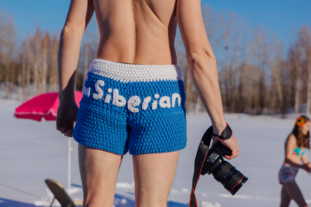 Novokuznetsk, Kemerovo region, Russia - 23 Feb, 2017 : White beaches of Siberia is an enterteiment activity where people playing beach games dressed in bikini in winter. Man in blue shorts with cameraのeditorial素材