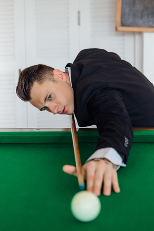 Young handsome man playing billiard game alone