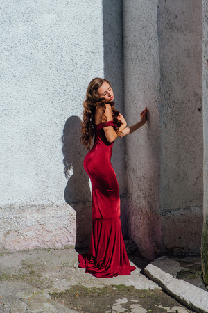 Beautiful young woman in a long red evening gown with a trainの写真素材