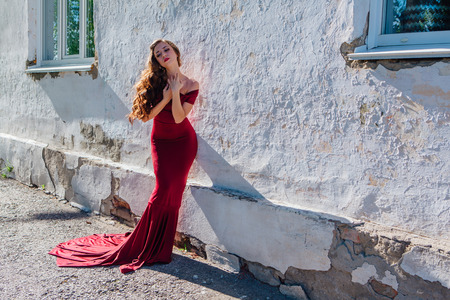 Beautiful young woman in a long red evening gown with a trainの写真素材
