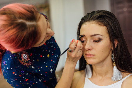 Make-up artist working in studio with young beautiful woman.の写真素材