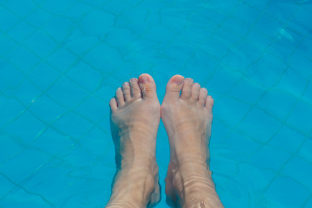 Bare female feet under the water of a swimming poolの写真素材