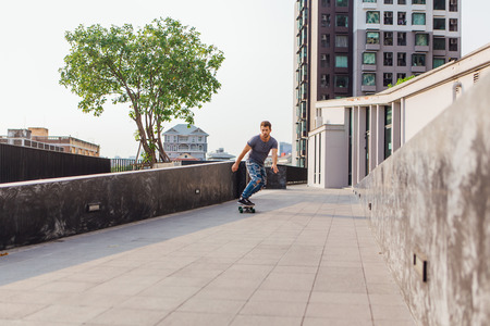Young handsome man with beard riding longboard on the street.の写真素材