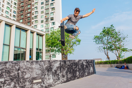 Young handsome man with beard on a skateboard jumping high and making trickの写真素材