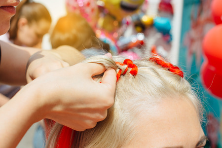 Hairdresser makes braids with red kanekalon. Close upの写真素材