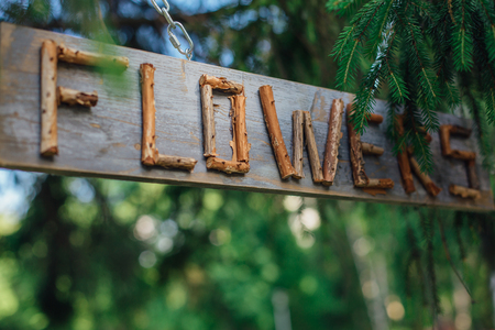 Word FLOWERS made of dry branches on the wooden sign under the tree. Copy space.の写真素材