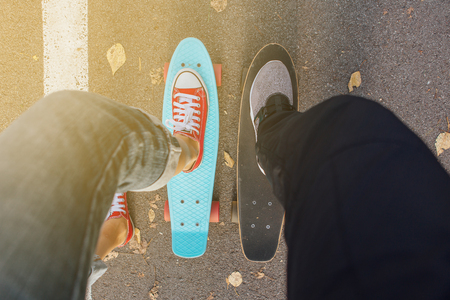 Close up of feet of a girl in red sneakers rides on blue penny skate board with pink wheels. Urban scene, city life. Sport, fitness lifestyle.の写真素材