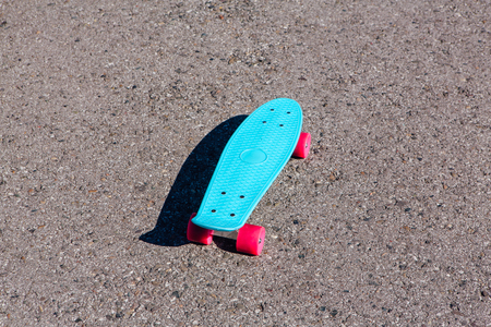 Blue plastic skateboard penny board with pink wheels stands on the track.の写真素材