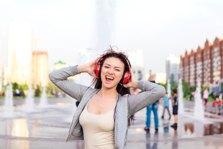 Girl listening to music streaming with headphones and dancing on the street.の写真素材