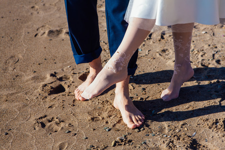 Front view of wedding couple's feet standing on the sandy beach.の写真素材