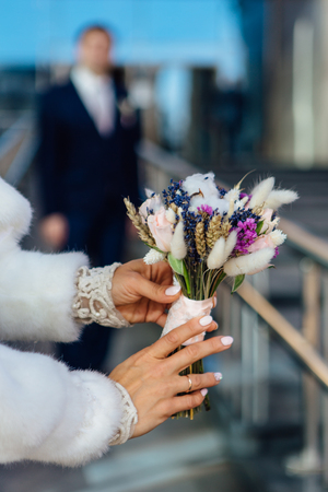 Beautiful wedding bouquet in the bride's hands with blured groom on the backgroundの写真素材