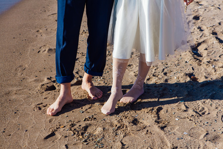 Front view of wedding couple's feet standing on the sandy beach.の写真素材