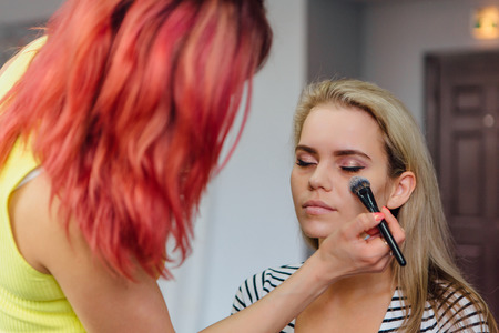 Make-up artist working in studio with young beautiful woman.の写真素材