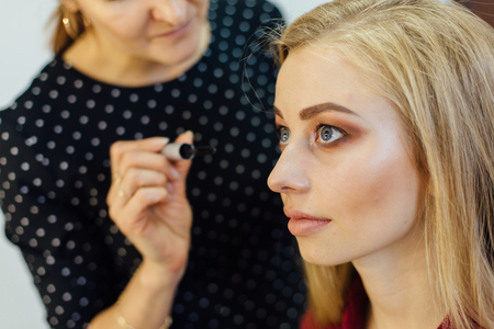 Make-up artist working in studio with young beautiful woman.の写真素材