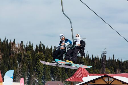 Sheregesh, Mountain Shoria, Kemerovo Region, Russia - April 6, 2018 : Couple of snowboarders on a ski lift in ski resortのeditorial素材