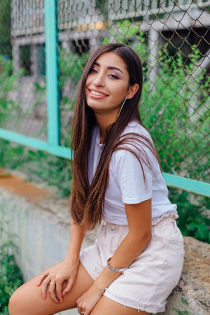 Portrait of a young brunette swag girl sitting next to rabitz fence.の写真素材