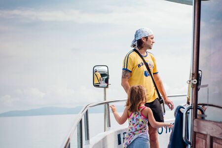 Surat Thai, Thailand - January 24, 2018: Tourists traveling on a ferry to the Koh Samui and Koh Phangan islands. Father with doughter standing on the deckのeditorial素材