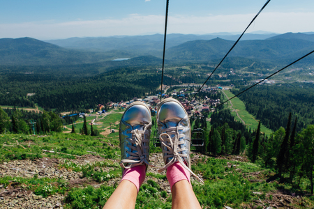 Silver shoes on feet during travel on mountain ski lift at summer time. The view from the mountain elevatorの写真素材