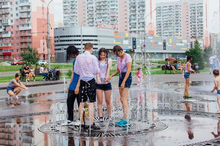 Novokuznetsk, Kemerovo Region, Russia - August 04, 2018: Happy teenagers splashing in a water of a city fountain and enjoying the cool streams of water in a hot day.のeditorial素材