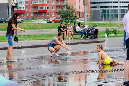 Novokuznetsk, Kemerovo Region, Russia - August 04, 2018: Happy teenagers splashing in a water of a city fountain and enjoying the cool streams of water in a hot day.のeditorial素材