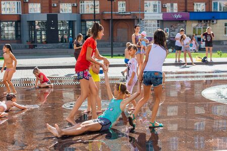 Novokuznetsk, Kemerovo Region, Russia - August 04, 2018: Happy children splashing in a water of a city fountain and enjoying the cool streams of water in a hot day.のeditorial素材