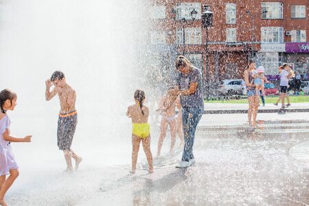 Novokuznetsk, Kemerovo Region, Russia - August 04, 2018: Happy children splashing in a water of a city fountain and enjoying the cool streams of water in a hot day.のeditorial素材
