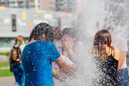 Novokuznetsk, Kemerovo Region, Russia - August 04, 2018: Happy teenagers splashing in a water of a city fountain and enjoying the cool streams of water in a hot day.のeditorial素材