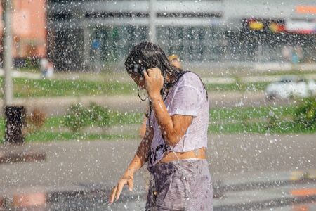 Novokuznetsk, Kemerovo Region, Russia - August 04, 2018: Happy teenagers splashing in a water of a city fountain and enjoying the cool streams of water in a hot day.のeditorial素材